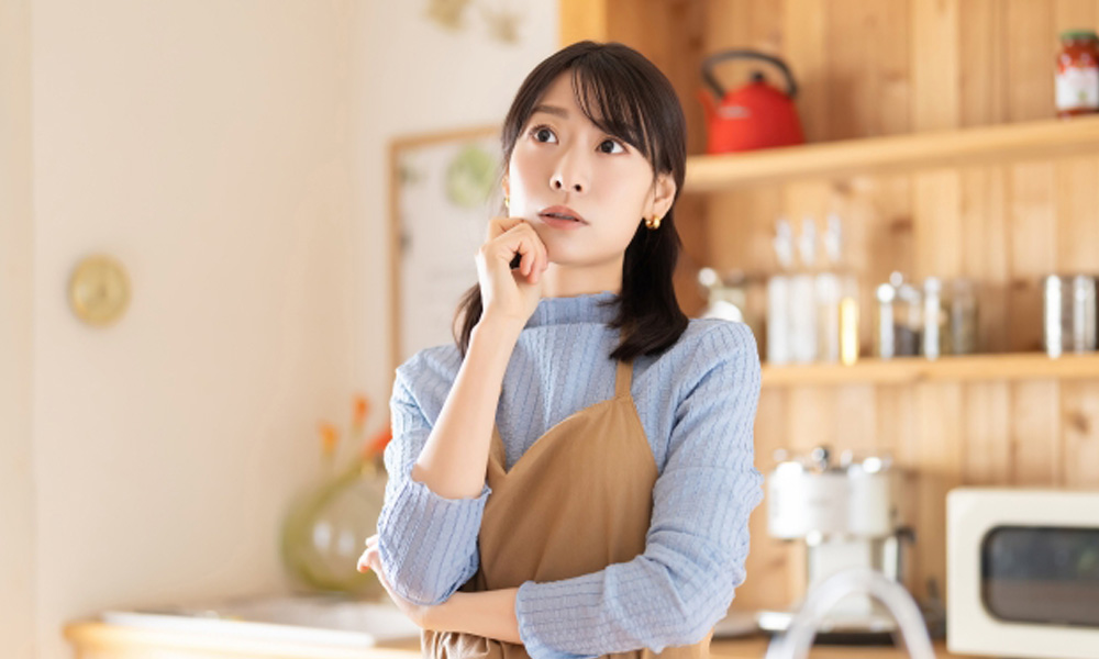 キッチンでケーキ作りに悩んでいる女性のイメージ