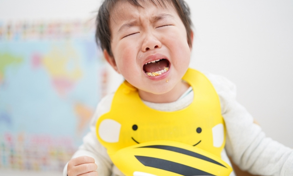 野菜を食べずに首を横に振るイヤイヤ期の子どものイラスト