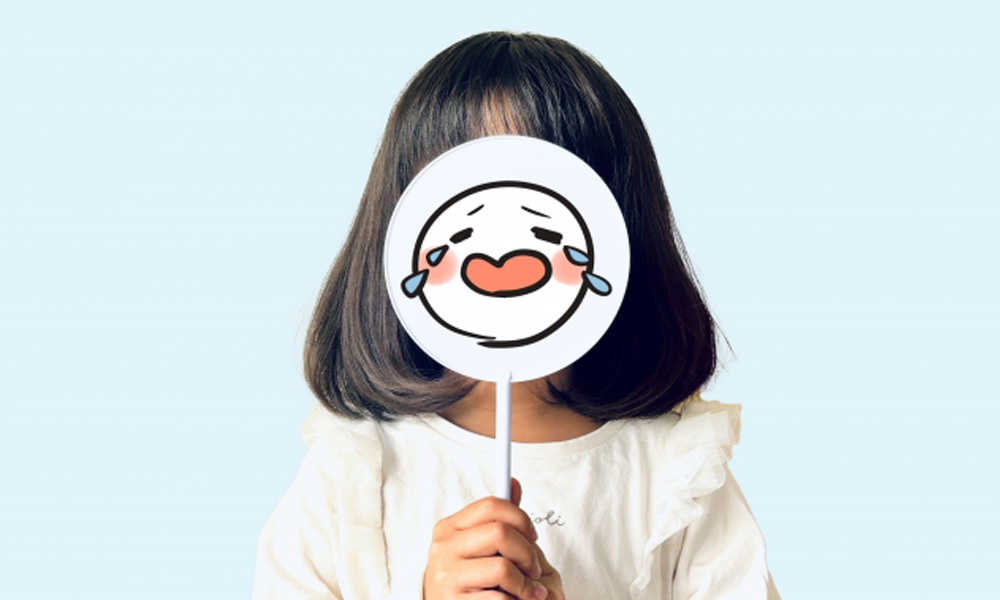 泣いている札をもって感情をアピールする子供のイメージ