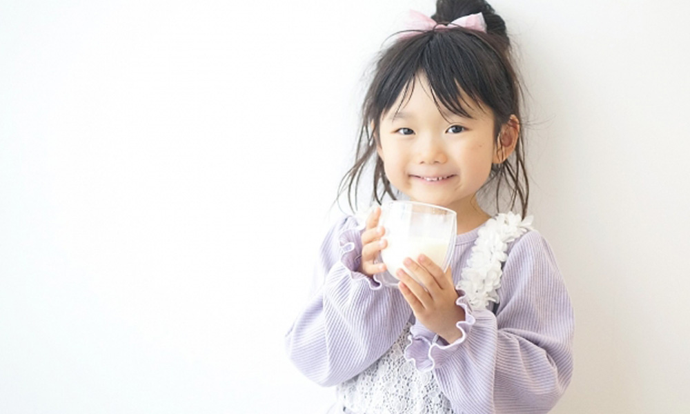 牛乳の入ったコップを手にもっている女の子のイメージ