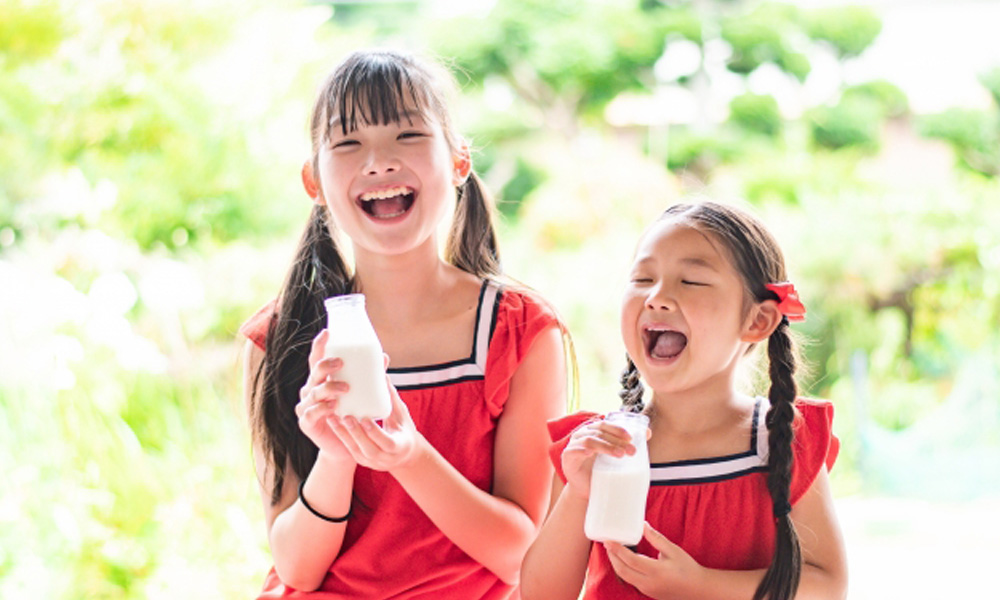 牛乳の入ったコップを手にもっている二人の女の子のイメージ