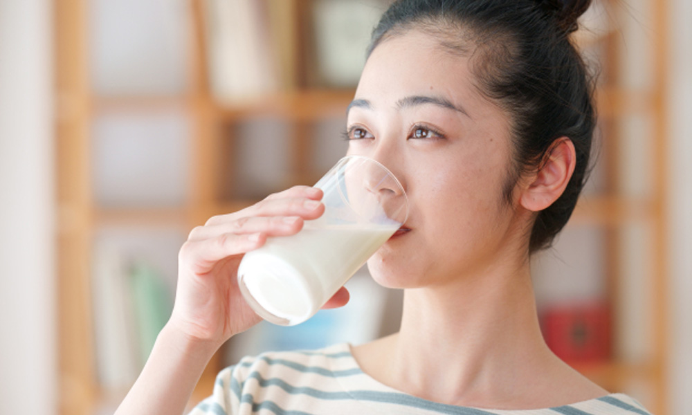 アーモンドミルクを美味しそうに飲んでいる女性のイメージ