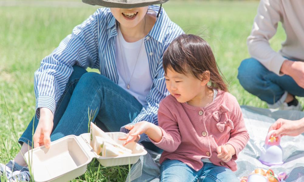 ピクニックで手作りのサンドウィッチを食べる家族のイメージ