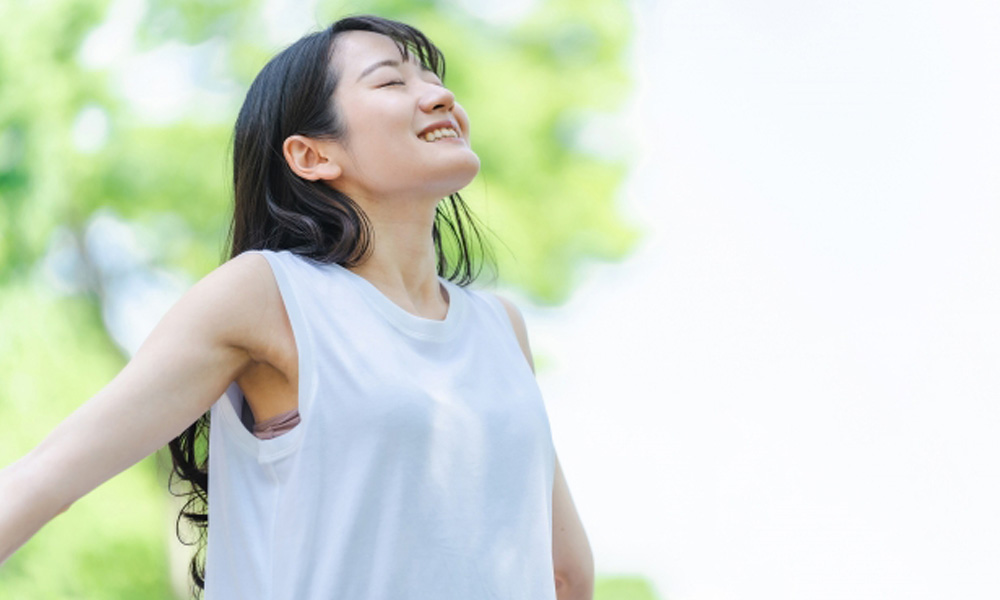 緑の中で健康的に体を伸ばす女性のイメージ