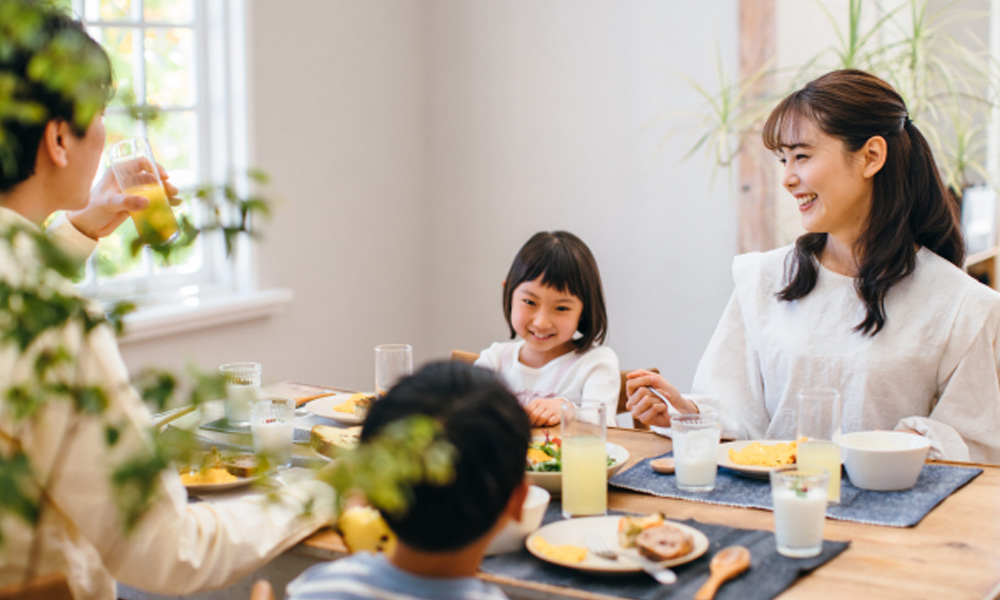 親と子供たち家族が笑顔で食事をとるイメージ