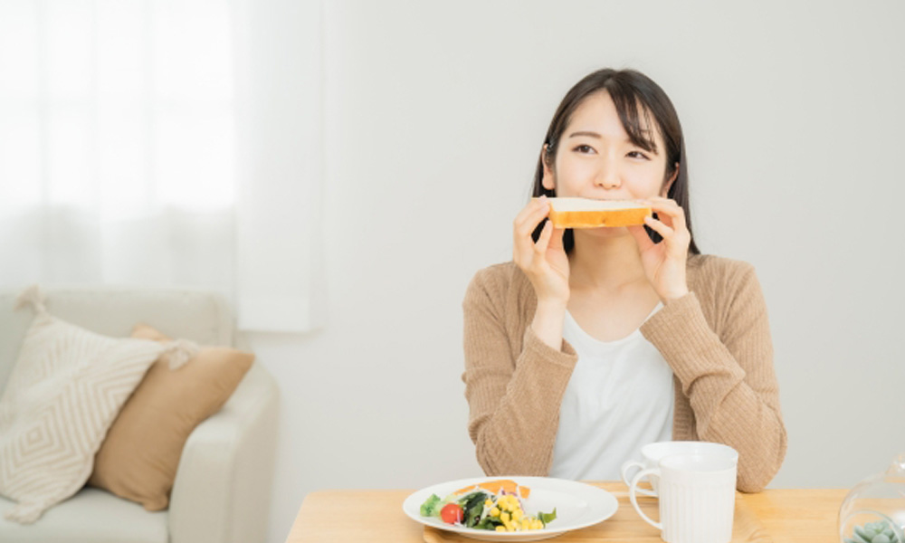 美味しそうに食パンを食べる女性のイメージ