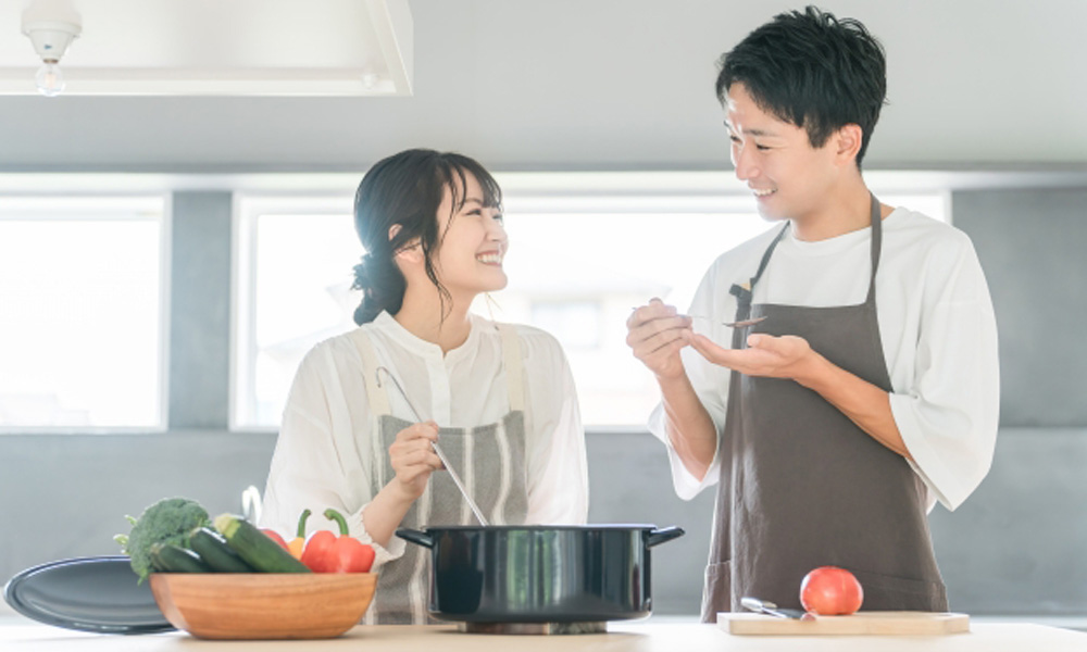 夫婦で料理を楽しみ、夫が味の確認をしているイメージ
