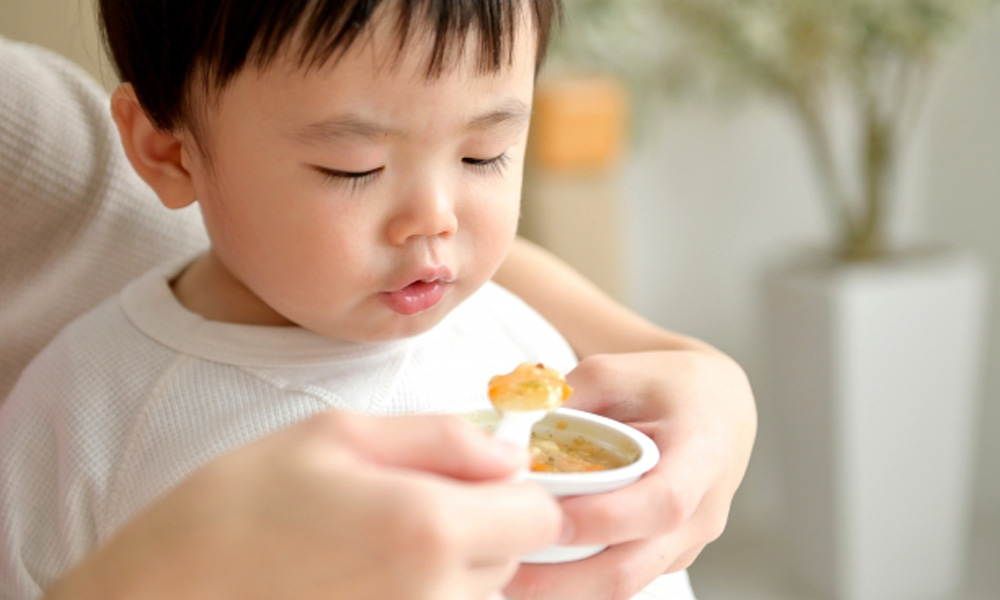 お母さんに離乳食を食べさせてもらっている子供のイメージ