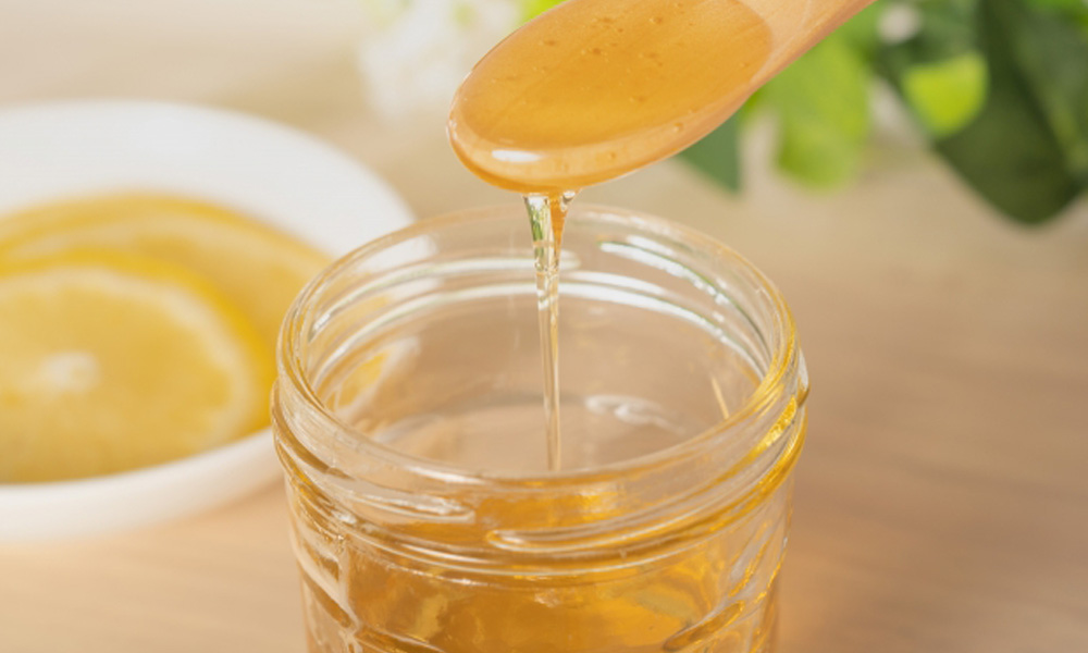 瓶に詰まったたっぷりの蜂蜜をスプーンですくっているイメージ