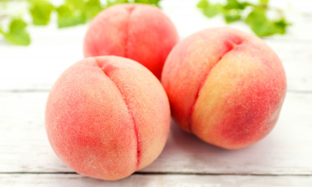 美味しそうな桃が3つ並んでテーブルの上に載っているイメージ