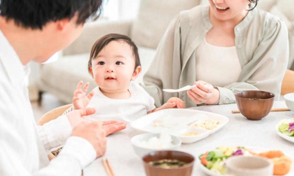 母親と父親が子供に離乳食を食べさせているイメージ