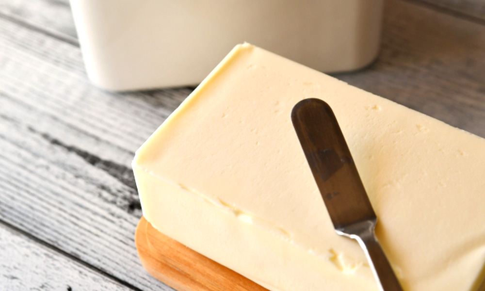 テーブルの上にのっているバターとバターナイフのイメージ