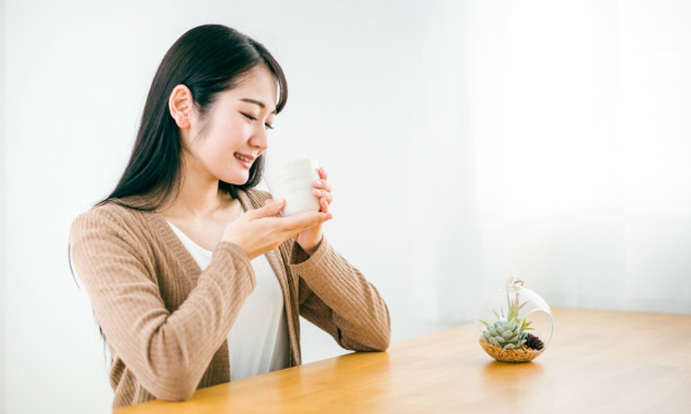 ゆっくり飲み物を飲んで落ち着く女性のイメージ