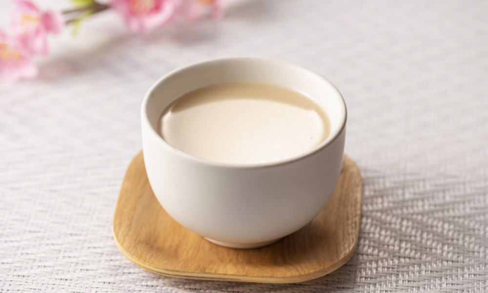 テーブルの上に置かれたコップに入った甘酒のイメージ