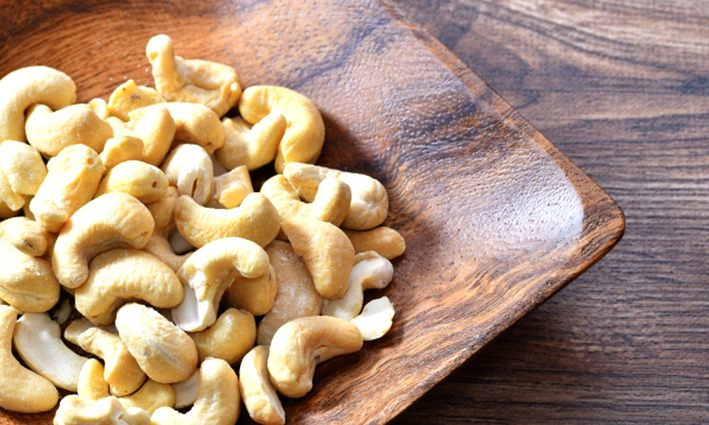 木の皿に盛り付けられたカシューナッツのイメージ