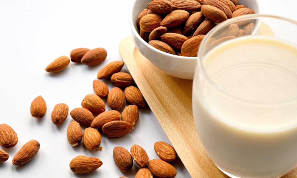 アーモンドミルクと大量のアーモンドがテーブルの上に載っているイメージ