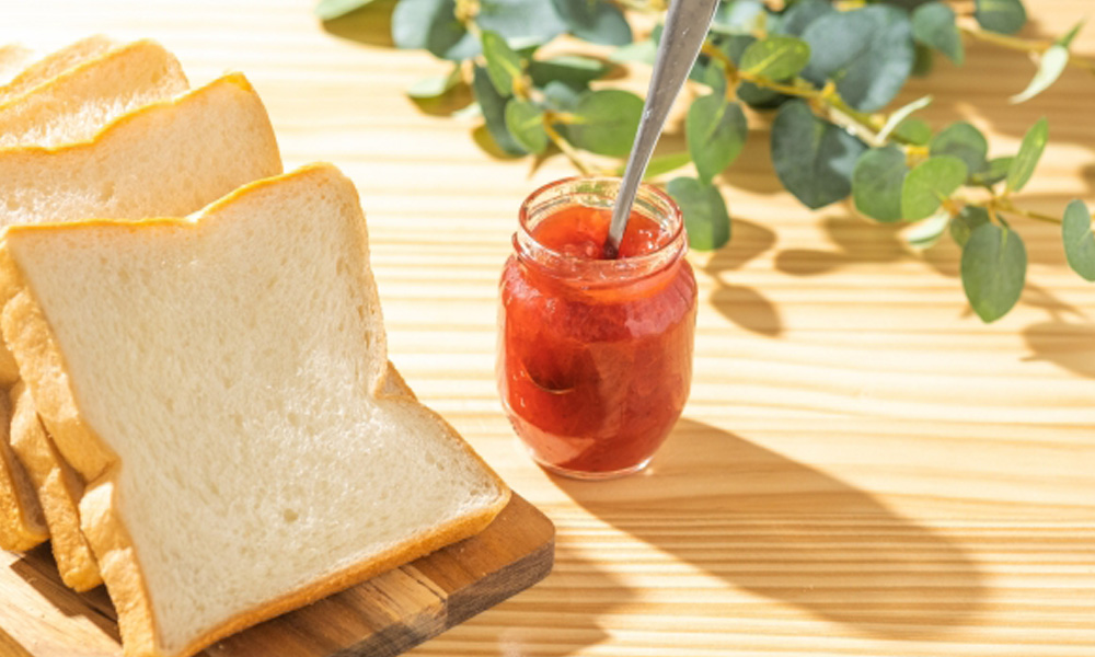 パンとイチゴジャムがテーブルにのっている朝食のイメージ