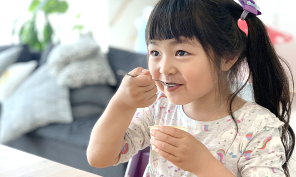 アイスクリームをスプーンですくって食べる少女のイメージ