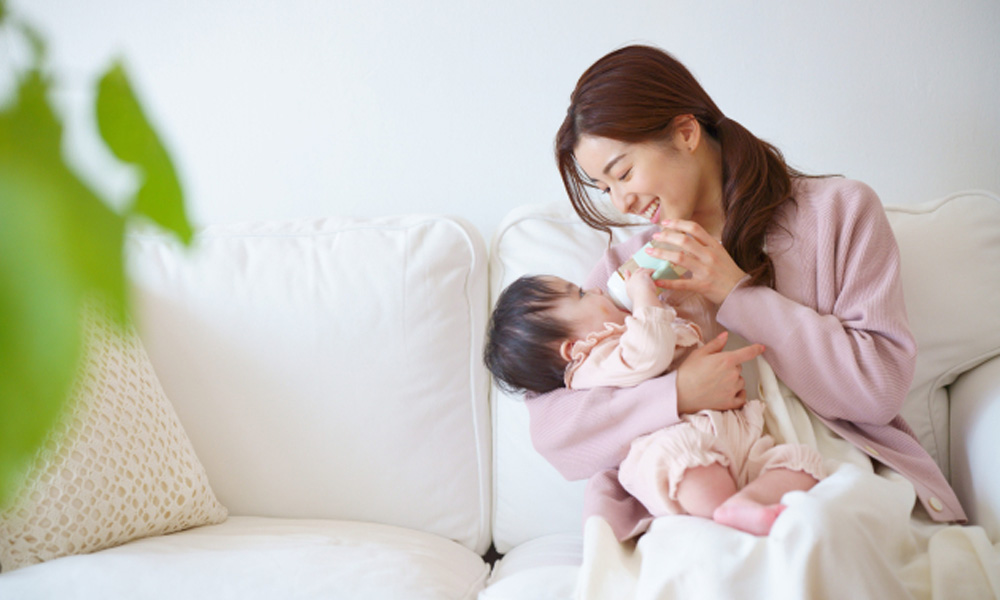 ミルクを飲む赤ちゃんを見つめるお母さんのイメージ