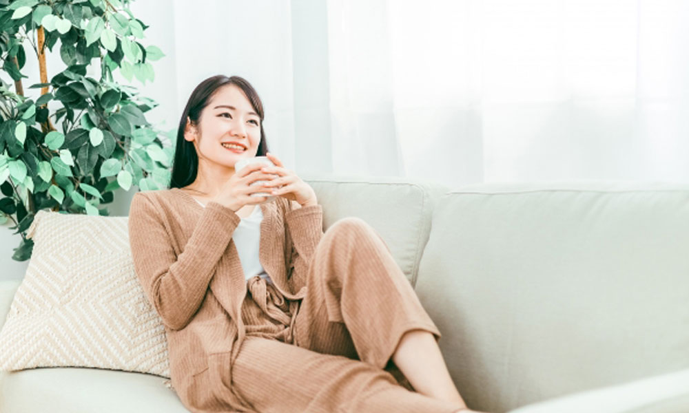 ゆっくりと飲み物を飲んでリラックスする女性のイメージ