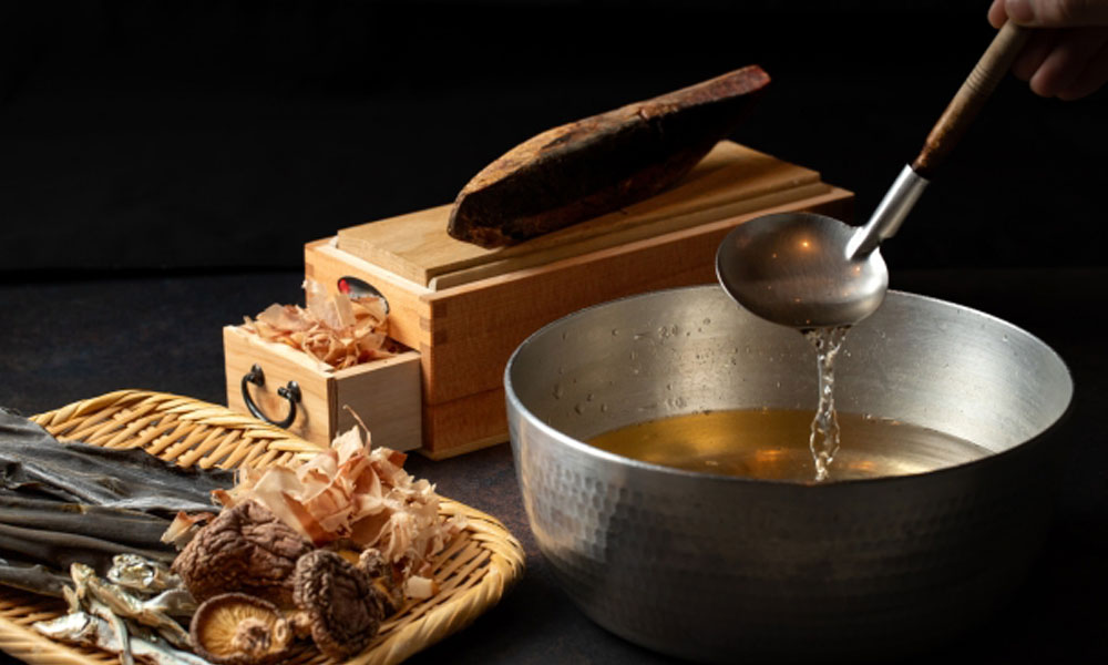 削りかつおや椎茸など出汁の元になる食材と出汁をお玉で掬っているイメージ