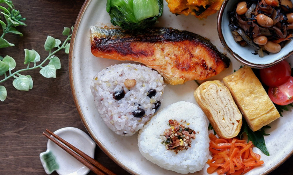 おにぎりや魚、野菜などを盛った朝食プレートのイメージ