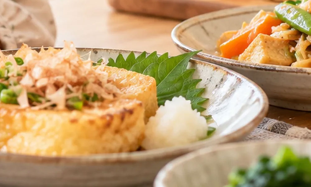 油揚げと野菜の煮物を盛り付けた食卓